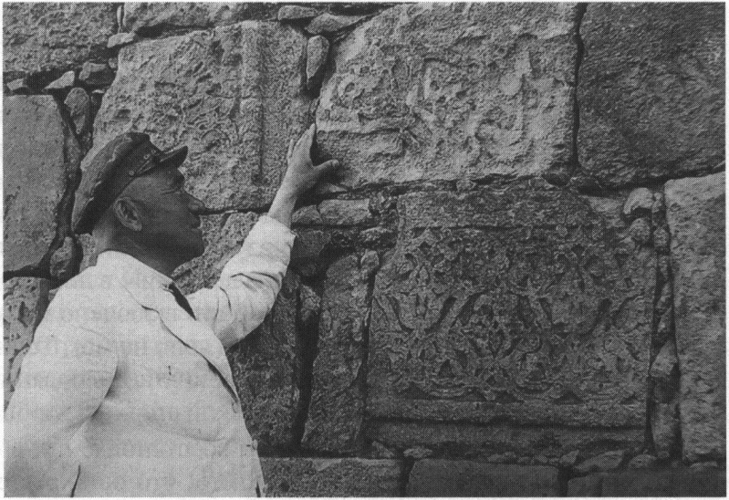 Осман Акчокраклы у стены, сложенной из камня разрушенных старинных зданий. Автор снимка неизвестен